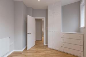 伦敦Kensington Olympia Apartment, Breakfast的一间空房间,有白色的橱柜和走廊