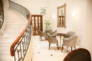 利马Los Tallanes Hotel & Suites的楼梯,房间里摆放着椅子和桌子