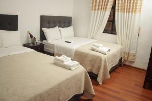 阿亚库乔Casona Valdelirios Hotel的一间卧室配有两张带白色床单的床