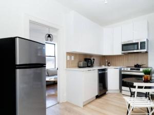 纽约Stunning 3BR Apartment in NYC!的厨房配有白色橱柜和黑色冰箱。