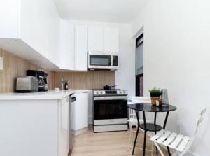 纽约Stunning 3BR Apartment in NYC!的厨房配有白色橱柜和桌椅