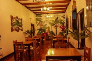 阿亚库乔Casona Valdelirios Hotel的一间带木桌和椅子的餐厅以及壁画