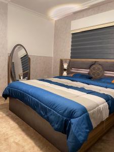 伊尔比德شركة مسايا لشقق المفروشة的卧室配有一张带镜子的蓝色和白色床