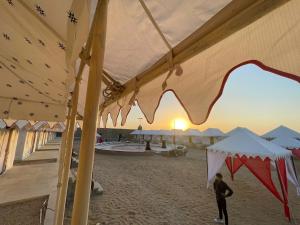 山姆Golden Empire luxury Resort的海滩上在帐篷下行走的人