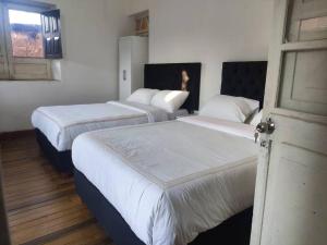 库斯科Departamento en Centro histórico de Cusco (PASEO LOS HEROES)的客房设有三张床、白色床单和窗户。
