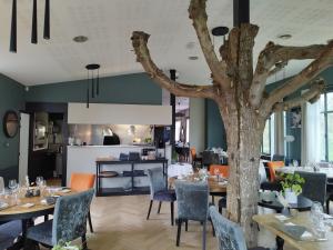 莱蓬德塞果树林餐厅酒店的一间设有桌椅的餐厅,还有一棵树