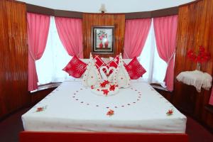 努沃勒埃利耶Heavenly Home Inn的一间卧室配有一张带红色和白色枕头的大床