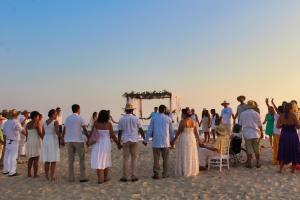 埃斯孔迪多港CasaPiedra的一群人站在海滩上婚礼仪式上