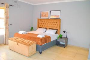 KingsmeadMt Pleasant - 4-Bed Villa in Harare Solar Power的一间卧室配有一张大床和一张搁脚凳