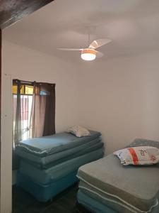 蒙加瓜Casa aconchegante beira mar的客房配有两张床垫和吊扇。
