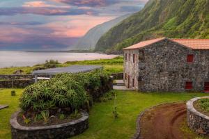 Fajã da Caldeira de Santo CristoKuanza Nature Experience, Fajã do Belo的山前的石头建筑