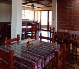 查查波亚斯Hostal Kollarón的一间设有桌椅的用餐室和砖墙