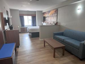 格里利Days Inn & Suites by Wyndham Greeley的酒店客房设有一张沙发和一张床
