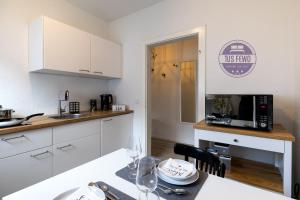 门兴格拉德巴赫2 Zi Wohnung inkl WLAN NETFLIX 3D Tour的厨房配有白色橱柜和带微波炉的桌子。