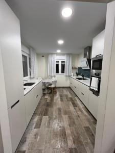 SobarzoLa Chabola的厨房铺有木地板,配有白色橱柜。
