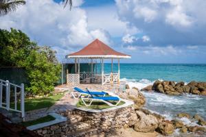 圣玛丽Chrisann's Beach Resort的一个带2把躺椅的凉亭和大海