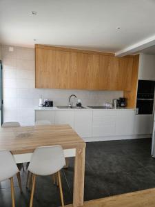卡列塔Pedreira apartment的厨房配有木桌和白色橱柜。