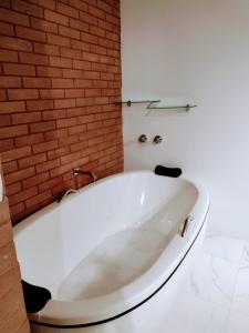 圣安东尼奥-杜皮尼亚尔Pousada Estância da Pinha的砖墙浴室内的白色浴缸