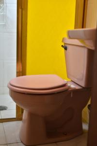 瓦曼特拉Hostal Quinto Sol Huamantla的浴室里设有粉红色的厕所,浴室里设有黄色的墙壁