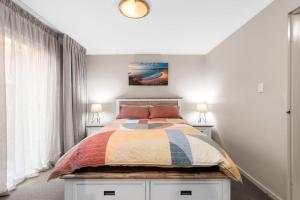 Surf BeachDenhams Beach Waterfront的一间卧室配有一张带五颜六色棉被的床