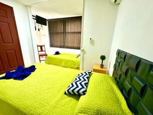 圣萨尔瓦多7hotel的一间卧室设有两张带黄床单的床和窗户。