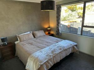 罗托鲁瓦Streamside Family Friendly Oasis with Spa的一间卧室设有一张床和一个大窗户