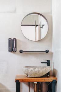 黄金海岸The Pink Hotel Coolangatta的浴室设有圆形镜子和石制水槽