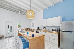 棕榈滩Beautiful and Spacious Mediterranean Style Villa on Palm Beach的厨房配有白色橱柜和一张带蓝色椅子的桌子。