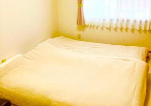 金泽ゲストハウス西金沢Smile&smile的窗户客房内的一张白色床