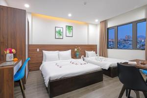 岘港TIDITEL Hotel and Apartment的酒店客房配有两张床和一张书桌