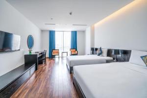 岘港Nostalgia Boutique Hotel的酒店客房带两张床和一张桌子以及椅子。