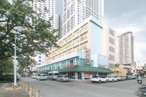 马尼拉Aloha Hotel Roxas Boulevard Manila的一座有汽车停在街道上的建筑,有高大的建筑