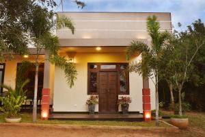 阿努拉德普勒Leaf Dew Resort的白色的房子,有棕色的门和树木