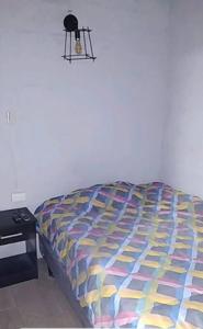 基多Minimalist House 1br El Bosque的卧室内一张带五颜六色棉被的床