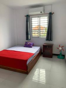 贡布Home Daun Kam的一间卧室配有一张带红色毯子的床和窗户。