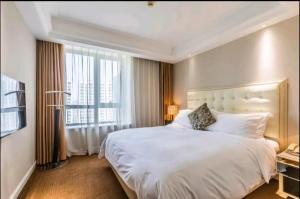 苏州苏州世豪国际大酒店  （原苏州世豪全套间酒店）的卧室设有一张白色大床和一扇窗户。
