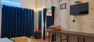 乌贾因Yadav homestay的一间设有蓝色窗帘和墙上电视的客房