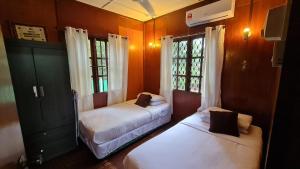 彭佳兰巴拉海滩Kampong Style Homestay Pengkalan Balak - Sea View的带2扇窗户的客房内的2张床
