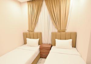 科威特الدانة للشقق الفندقية的配有窗帘的客房内的两张床