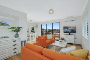 伯马吉Bermagui Townhouse - Amazing views & location的客厅配有橙色沙发和桌子