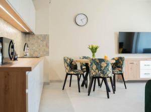 尤斯托尼莫斯基Apartament Morski Wiatr的厨房配有桌椅和墙上的时钟