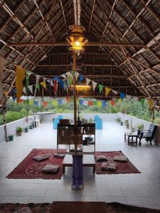 黎明之村WoodPacker Hostel Auroville Pondicherry的大房间设有一张桌子和悬挂着旗帜的天花板