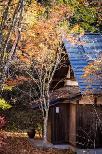 长野Villa Iizuna Plateau -飯綱高原の山荘-的蓝屋顶房子旁边的一棵树