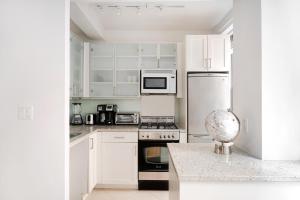 纽约Cozy Studio Apartment的白色的厨房配有白色橱柜和电器