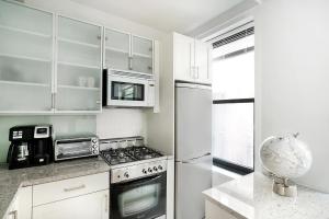 纽约Cozy Studio Apartment的白色的厨房配有炉灶和冰箱。
