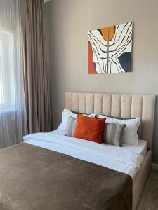 阿斯塔纳Уютная студия с видом на Ботанический парк的一间卧室配有一张带橙色和白色枕头的大床