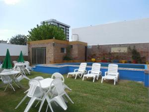 维拉卡洛斯帕兹维克多酒店的一组白色的椅子和桌子,旁边是游泳池