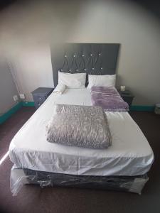 伯诺尼Prime Guest Inn的卧室配有一张白色大床和床头板