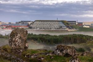 托尔斯港Hilton Garden Inn Faroe Islands的河中一座大建筑,有雾