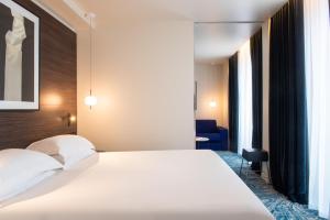巴黎金色郁金香诺阿伊剧院酒店的卧室配有白色的床和蓝色椅子
